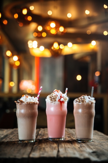 Three different sweet milkshakes on wooden table