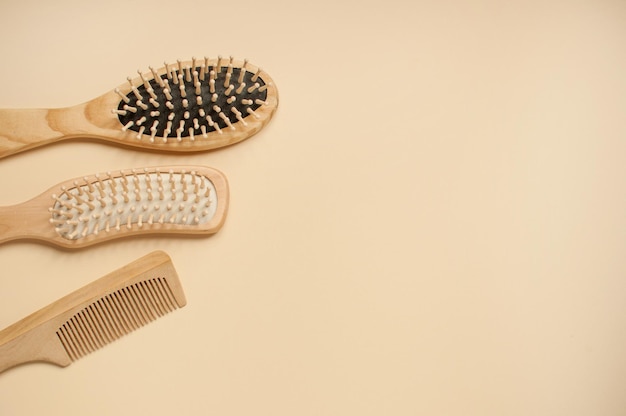 Three different wooden combs on a beige background with space for text