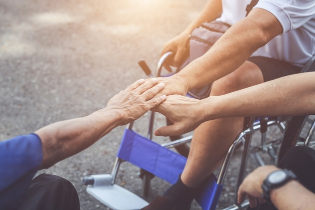 Three of disabled people sitting on wheelchair and putting their hand together