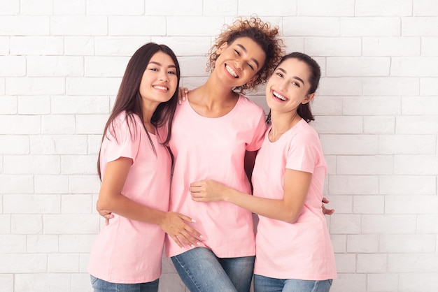 Three Diverse Breast Cancer Volunteers Girls Embracing Over White Background