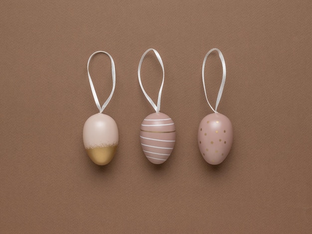 Three Easter eggs with ribbons on a brown background Flat lay