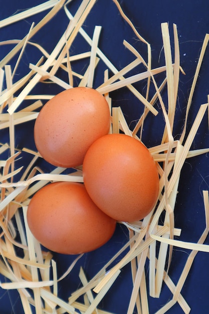 Photo three eggs are placed in a pile of straw