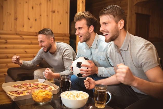 The three emotion men watch a football and gesture