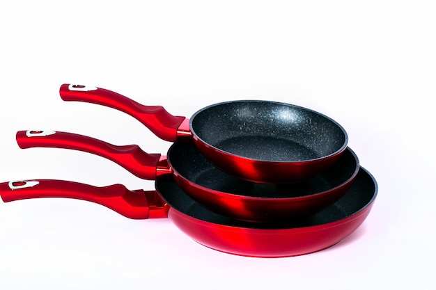 Three empty black-red frying pans on white