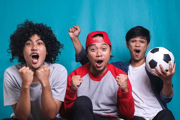 Three excited soccer fans cheering for favorite sport team with bright expression. Concept of sport,