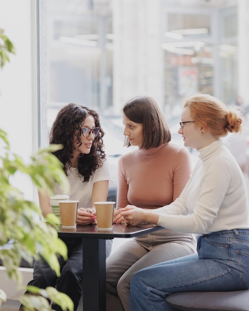 Three female colleagues or students are working on a laptop and discussing a project or creative