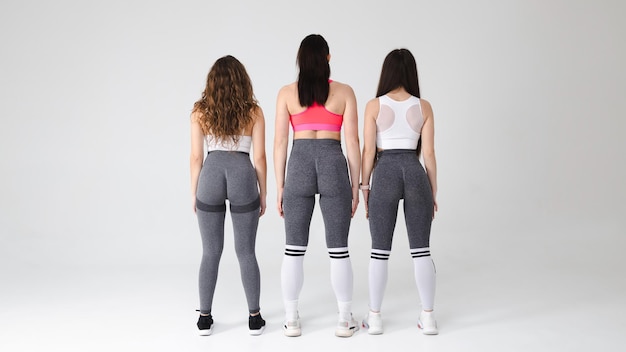 Three fitness girls are standing with nice buttocks