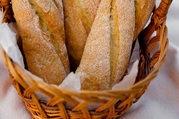 Three fresh baguettes lie in a wicker basket