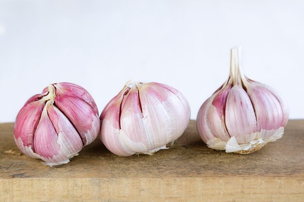 Three fresh garlic on old wooden table and white backgroundxA