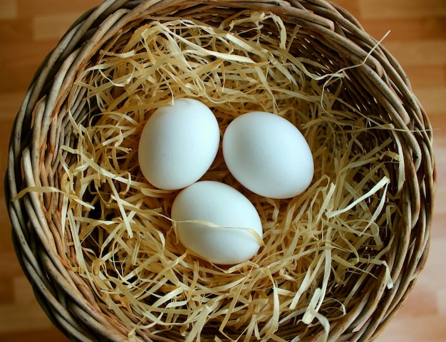 Three Freshly Picked Eggs In A Wooden Shavings Inside A Wicker Pot Top View Stock Photo