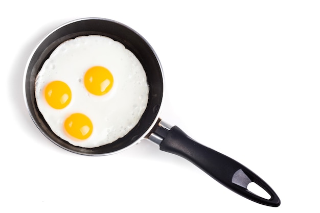 Three fried egg on teflon pan without oil isolated on white