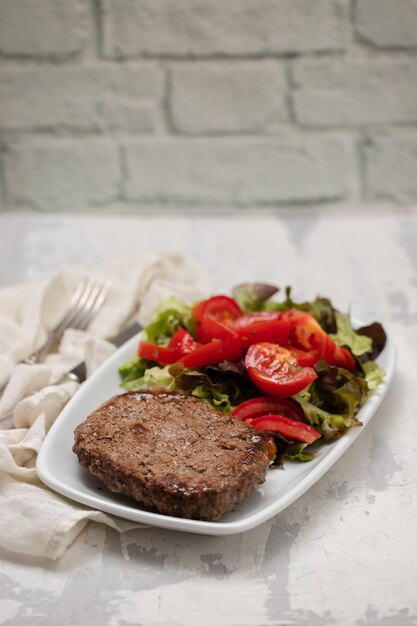 Three fried ground meat with fresh salad on white plate