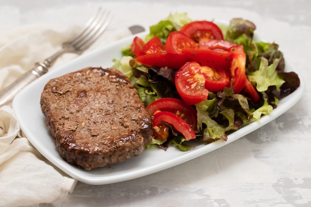 Three fried ground meat with fresh salad on white plate