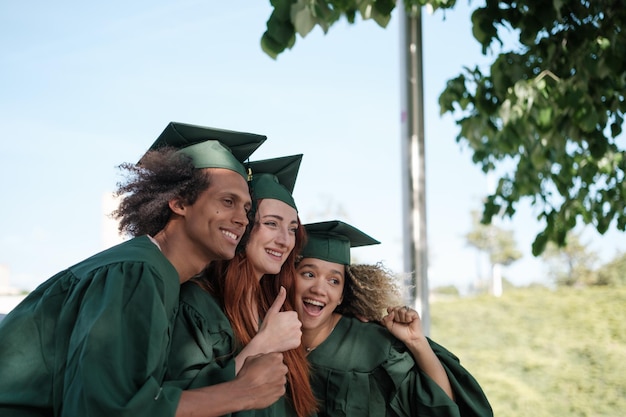 Three friends taking a photo celebrating their university graduation with the border suit Concept graduation university studies