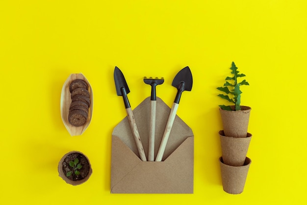 Photo three garden tools in a craft envelope and cardboard glasses on yellow