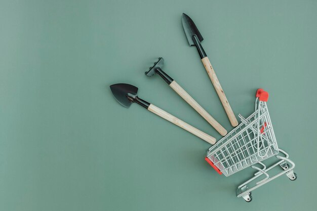 Three gardening tools and a shopping trolley on green