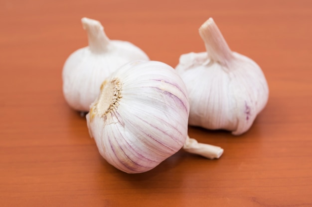 Three garlics on a wooden table.