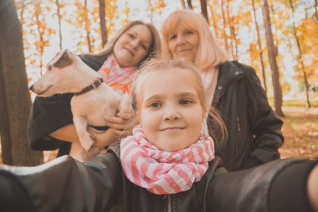 Three generations of women and dog feel fun look at camera posing for selfportrait picture together