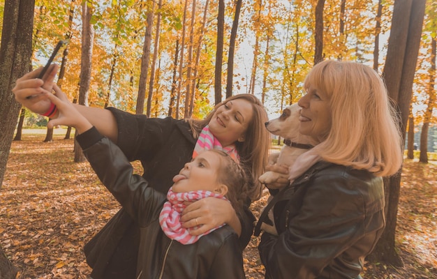 Three generations of women and dog feel fun look at camera posing for selfportrait picture together