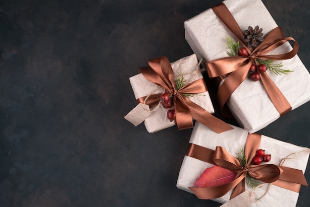 Three gifts in beige wrapping paper tied with brown ribbons on brown