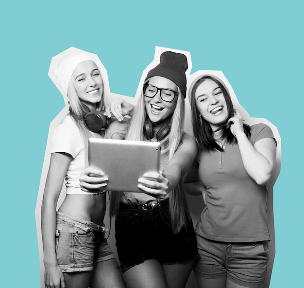 Three girls friends taking selfie with digital tablet studio shot over gray background