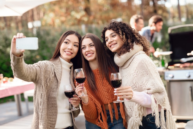 Three girls make selfie during a picnic with friends.