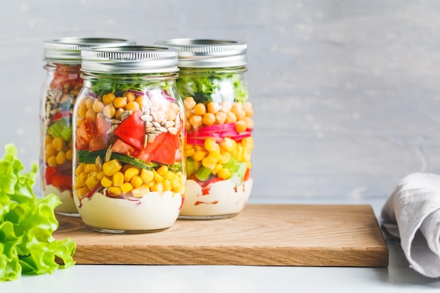 Three glass jars with layering various vegan salads for healthy lunch Extrem close up The concept of fitness and vegetarian food