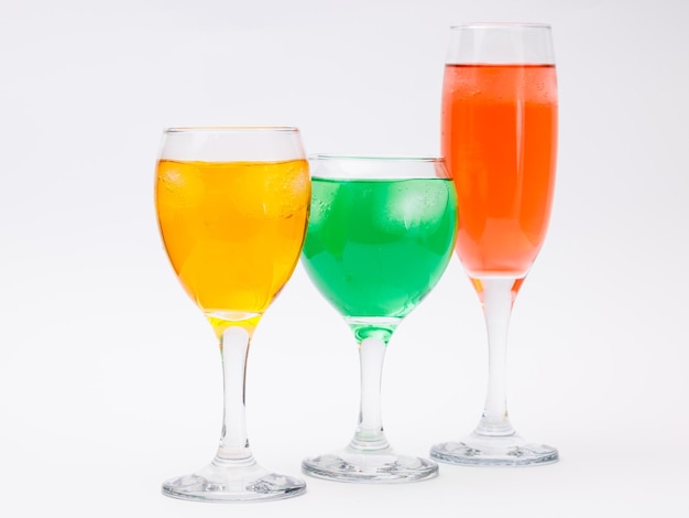 Three glasses with different liquors on white background.