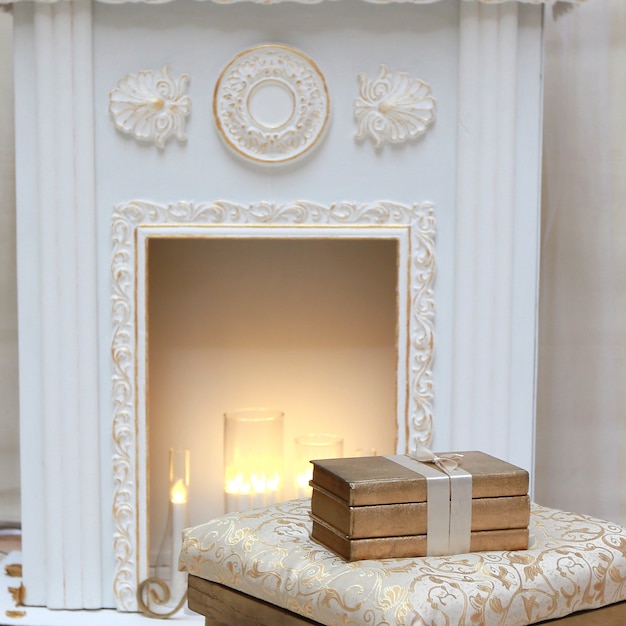 Three golden books on the pouf near the hearth