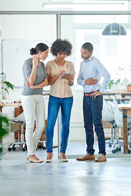 Three great minds think alike Shot of a group of office colleagues having a discussion over a digital tablet