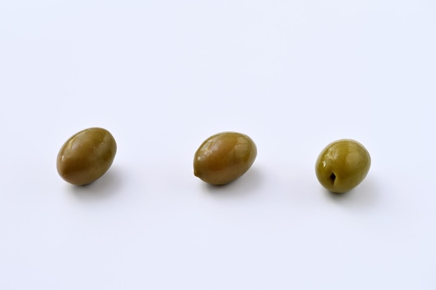 Photo three green pickled olives on a white background