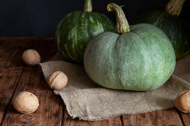 Three green pumpkins on a dark 