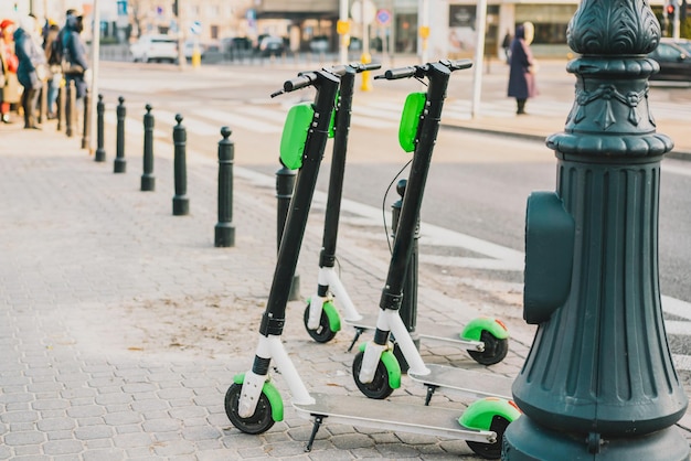 Three green rental electric scooter standing on a sidewalk City Transport Pathway Outdoor Electric urban transportation