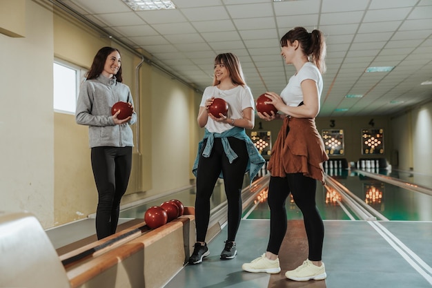 Three happy female friends having fun in the bowling club.