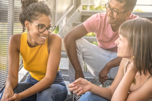 Three happy people chatting, youth generation z lifestyle, multicultural group having fun outdoor