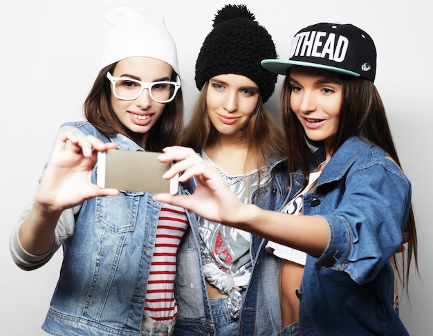 Three happy teenage girls with smartphone taking selfie