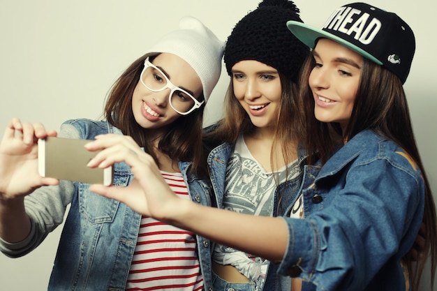 Three happy teenage girls with smartphone taking selfie