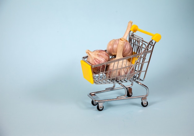 Three heads of garlic lie in a supermarket basket