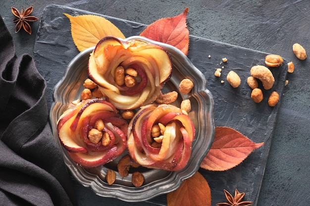 Three homemade puff pastries with rose shaped apple slices on metal plate, flat lay