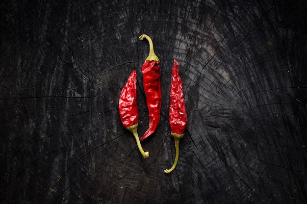 Three hot red peppers on black board