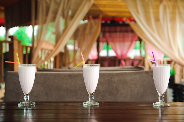 Three jars of pink berry milkshakes with straws on old wooden table.