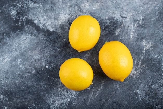 Three juicy ripe lemons placed marble surface