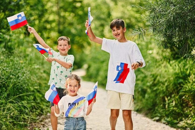 Three kids hold slovenian flags in Triglav National Park Slovenia