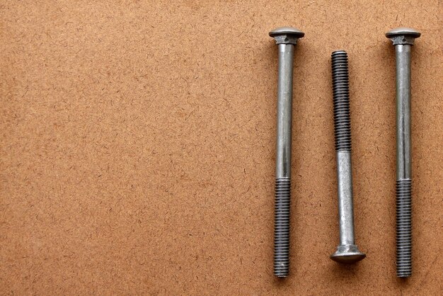 Three large screws used to fix wood on a plywood texture