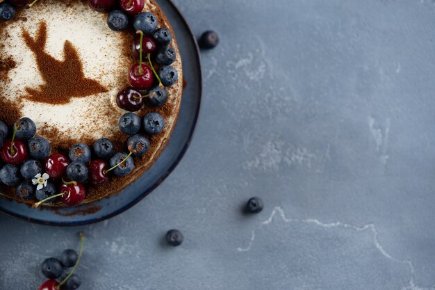 Three layers bird cherry cake with sour cream decorated with fresh berries and cherries