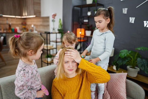 Three little girls are doing their moms hair