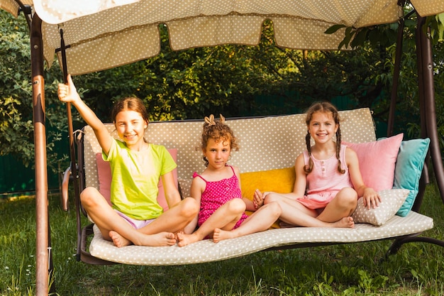 Three lovely sisters on soft garden swing