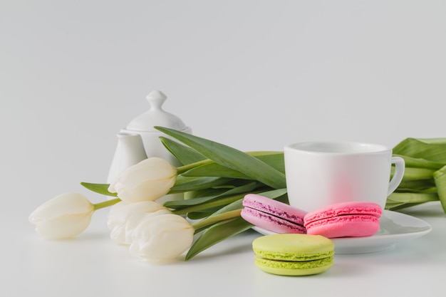 Three macaroons, cup of coffee and white flowers tulip