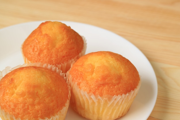 Three Madeleine Cupcakes on White Plate Served on Wooden Table