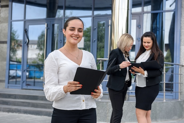 Three managers with folders posing outside office building